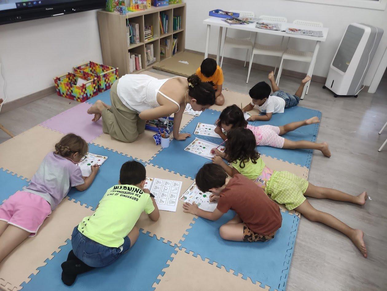 La teacher jugant amb els nens a terra